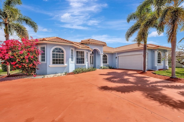 1897 SW Citation Ave, Port Saint Lucie, FL 34953 - mediterranean / spanish-style house with stucco siding, an attached garage, concrete driveway, and a tiled roof