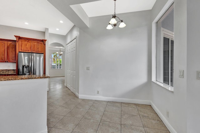 1897 SW Citation Ave, Port Saint Lucie, FL 34953 - kitchen featuring a chandelier, stainless steel fridge, light tile patterned floors, baseboards, and dark stone countertops