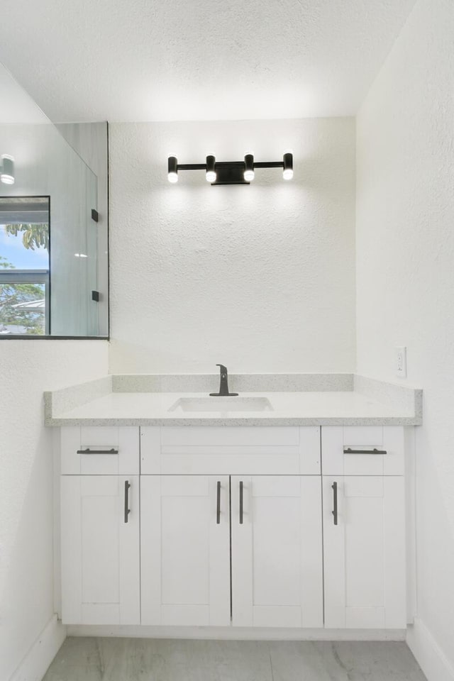 4873 SE Pilot Way, Stuart, FL 34997 - bathroom with baseboards, vanity, a textured ceiling, marble finish flooring, and a textured wall
