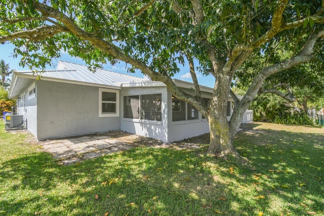 4873 SE Pilot Way, Stuart, FL 34997 - view of property exterior with a sunroom, stucco siding, central air condition unit, and a lawn