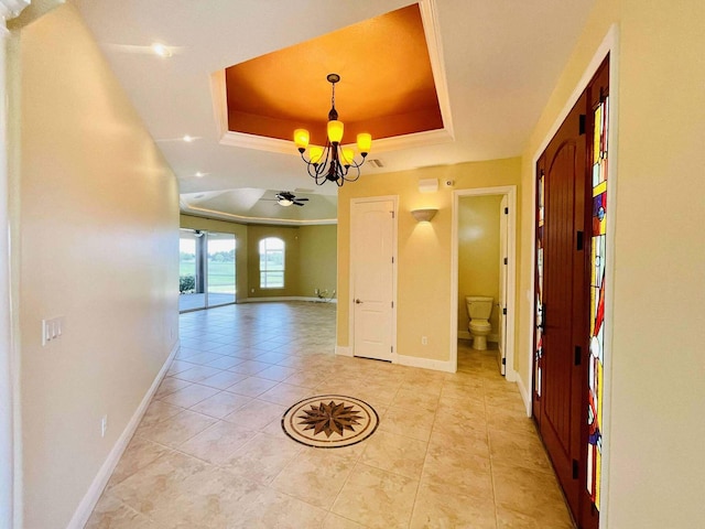1036 Greenway Ter, Sebring, FL 33876 - corridor featuring a chandelier, a tray ceiling, baseboards, and light tile patterned floors
