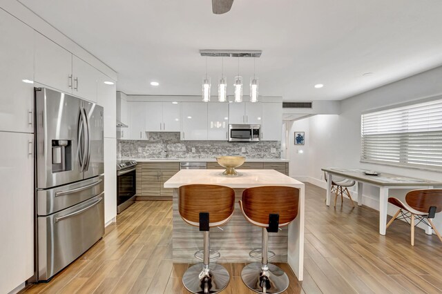 187 Seville H, Delray Beach, FL 33446 - kitchen with stainless steel appliances, modern cabinets, light wood-style floors, light countertops, and decorative backsplash
