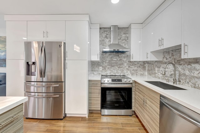 187 Seville H, Delray Beach, FL 33446 - kitchen featuring appliances with stainless steel finishes, wall chimney range hood, a sink, light countertops, and wood tiled floors