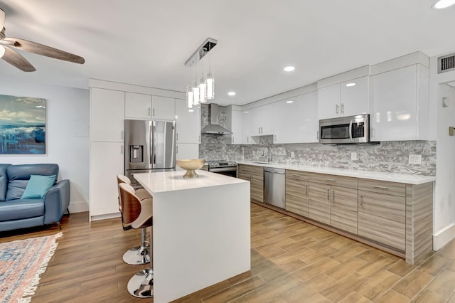 187 Seville H, Delray Beach, FL 33446 - kitchen with appliances with stainless steel finishes, wall chimney range hood, ceiling fan, decorative backsplash, and recessed lighting