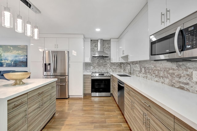 187 Seville H, Delray Beach, FL 33446 - kitchen with stainless steel appliances, wall chimney exhaust hood, a sink, tasteful backsplash, and white cabinets
