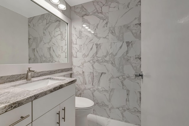187 Seville H, Delray Beach, FL 33446 - bathroom featuring vanity, toilet, marble look tiles, and a marble finish shower