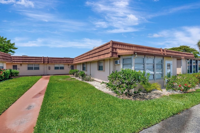 187 Seville H, Delray Beach, FL 33446 - view of front facade with stucco siding, mansard roof, a front yard, and a wall unit AC