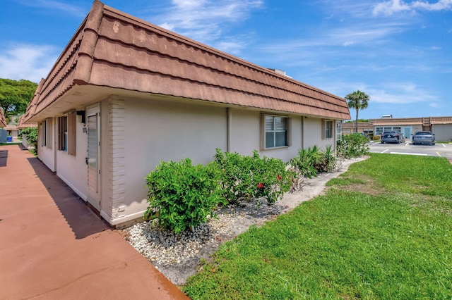 187 Seville H, Delray Beach, FL 33446 - view of side of home with stucco siding and a lawn