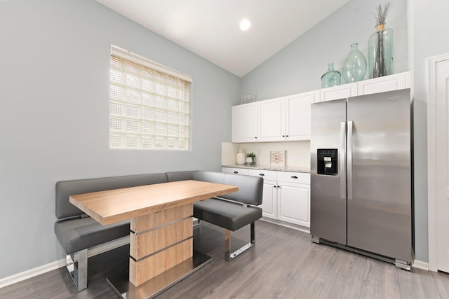 3288 SW Majestic Ct, Palm City, FL 34990 - kitchen with stainless steel fridge with ice dispenser, breakfast area, wood finished floors, white cabinets, and high vaulted ceiling