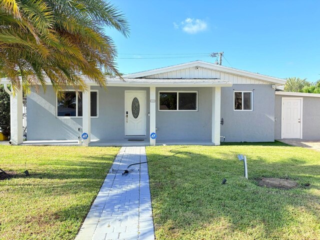 1034 Almeria Rd, West Palm Beach, FL 33405 - ranch-style house featuring a front lawn and stucco siding