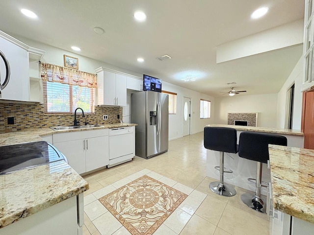 1034 Almeria Rd, West Palm Beach, FL 33405 - kitchen featuring dishwasher, a sink, stainless steel refrigerator with ice dispenser, decorative backsplash, and light tile patterned flooring