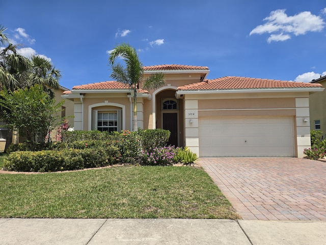 5704 Spanish River Rd, Fort Pierce, FL 34951 - mediterranean / spanish house featuring an attached garage, stucco siding, a front lawn, a tile roof, and decorative driveway