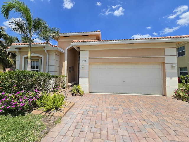 5704 Spanish River Rd, Fort Pierce, FL 34951 - mediterranean / spanish-style house featuring stucco siding, a garage, decorative driveway, and a tile roof