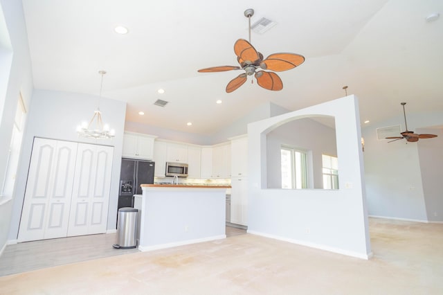 5704 Spanish River Rd, Fort Pierce, FL 34951 - kitchen with a ceiling fan, stainless steel microwave, vaulted ceiling, open floor plan, and white cabinetry