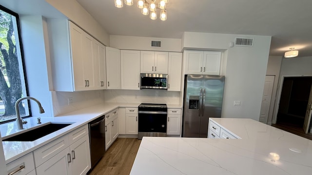 5800 Coach House Cir Unit B, Boca Raton, FL 33486 - kitchen with stainless steel appliances, a sink, decorative backsplash, a chandelier, and white cabinets