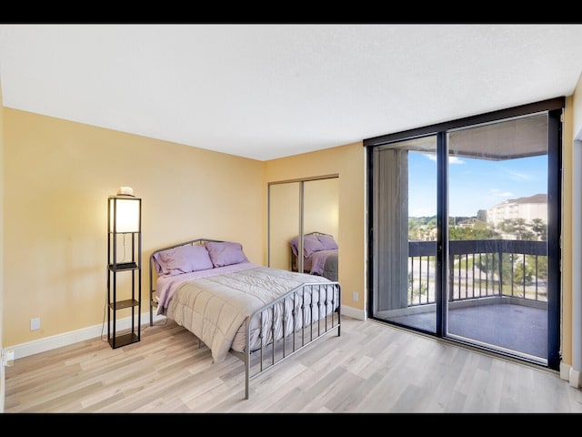 2400 Presidential Way Unit 401, West Palm Beach, FL 33401 - bedroom featuring light wood-style flooring, access to outside, baseboards, a closet, and a wall of windows