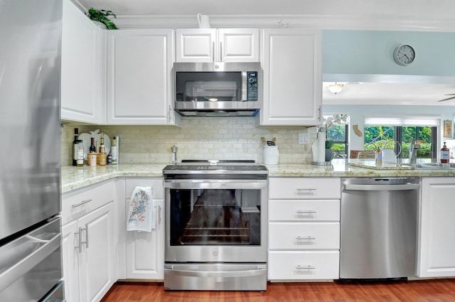 438 Pine Villa Dr, Atlantis, FL 33462 - kitchen featuring stainless steel appliances, decorative backsplash, white cabinets, and light wood-type flooring