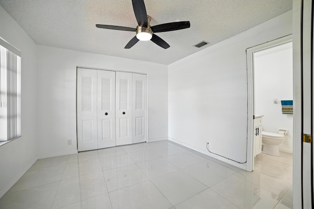 5242 Privet Pl Unit C, Delray Beach, FL 33484 - unfurnished bedroom with a textured ceiling, baseboards, a closet, light tile patterned flooring, and ceiling fan