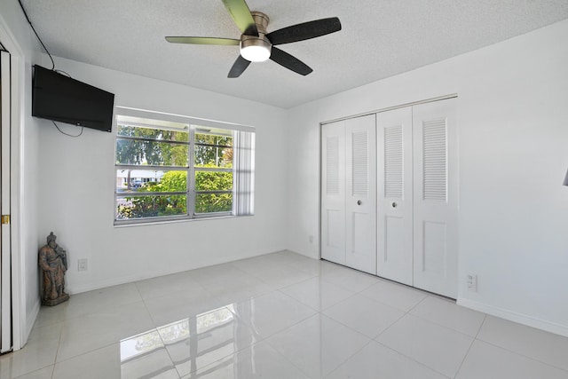 5242 Privet Pl Unit C, Delray Beach, FL 33484 - unfurnished bedroom featuring a textured ceiling, tile patterned floors, a closet, baseboards, and ceiling fan
