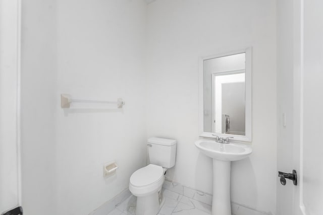 5761 Spanish River Rd, Fort Pierce, FL 34951 - bathroom with marble look tiles, toilet, a sink, and baseboards