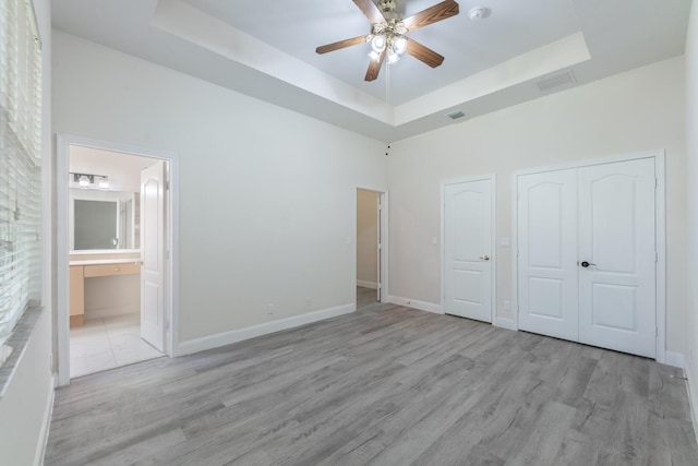 5761 Spanish River Rd, Fort Pierce, FL 34951 - unfurnished bedroom with a raised ceiling, light wood-type flooring, ensuite bath, and baseboards
