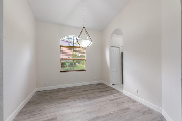 5761 Spanish River Rd, Fort Pierce, FL 34951 - unfurnished room featuring arched walkways, light wood-style floors, vaulted ceiling, baseboards, and a chandelier