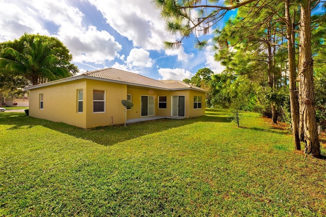 5761 Spanish River Rd, Fort Pierce, FL 34951 - rear view of property featuring stucco siding, a tile roof, and a yard