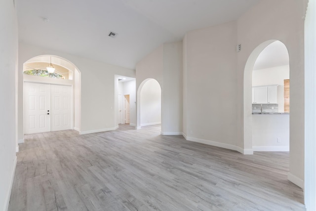 5761 Spanish River Rd, Fort Pierce, FL 34951 - empty room with light wood finished floors, arched walkways, baseboards, and high vaulted ceiling