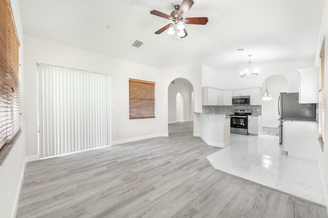 5761 Spanish River Rd, Fort Pierce, FL 34951 - unfurnished living room featuring arched walkways, a ceiling fan, a chandelier, baseboards, and vaulted ceiling