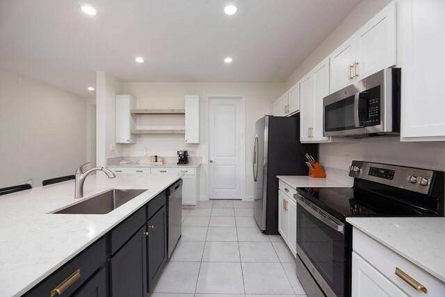 7499 NW Deysbrook Ln, Port Saint Lucie, FL 34987 - kitchen with stainless steel appliances, a sink, white cabinetry, open shelves, and light stone counters