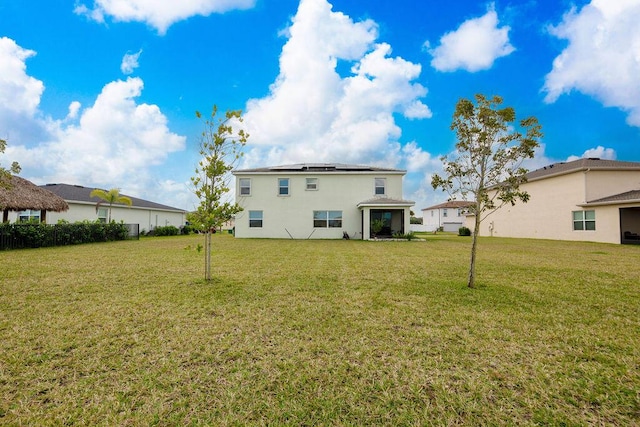 7499 NW Deysbrook Ln, Port Saint Lucie, FL 34987 - back of property featuring solar panels, a lawn, and stucco siding