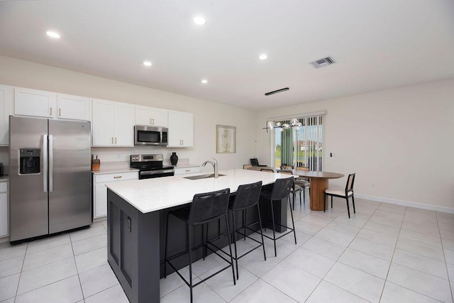 7499 NW Deysbrook Ln, Port Saint Lucie, FL 34987 - kitchen with stainless steel appliances, a sink, light countertops, white cabinets, and an island with sink