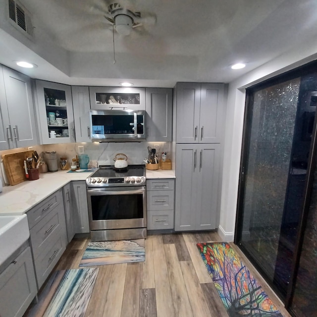 54 Piedmont Unit B, Delray Beach, FL 33484 - kitchen featuring gray cabinetry, stainless steel appliances, light wood finished floors, glass insert cabinets, and recessed lighting