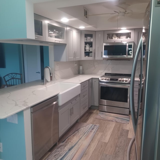 54 Piedmont Unit B, Delray Beach, FL 33484 - kitchen featuring stainless steel appliances, light wood-style flooring, light stone countertops, and backsplash