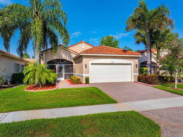 415 NW Granville St, Port Saint Lucie, FL 34986 - mediterranean / spanish house with a garage, decorative driveway, stucco siding, a tile roof, and a front yard