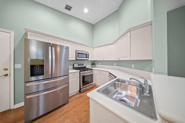 415 NW Granville St, Port Saint Lucie, FL 34986 - kitchen with appliances with stainless steel finishes, light countertops, white cabinets, light wood-style floors, and a towering ceiling