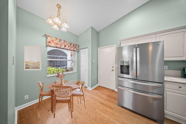 415 NW Granville St, Port Saint Lucie, FL 34986 - dining space with vaulted ceiling, light wood-style flooring, a chandelier, and baseboards
