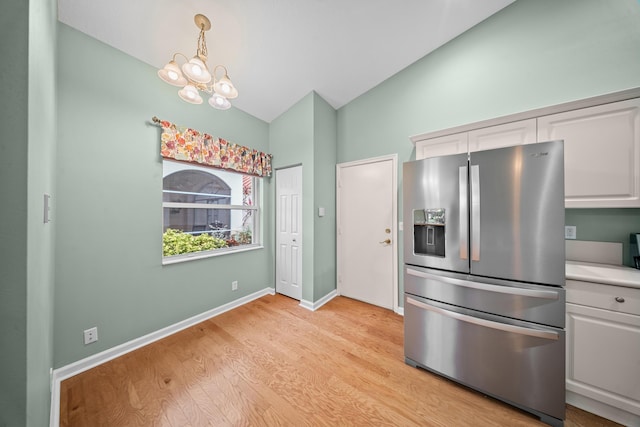 415 NW Granville St, Port Saint Lucie, FL 34986 - kitchen with stainless steel fridge with ice dispenser, vaulted ceiling, light wood-type flooring, a chandelier, and white cabinets