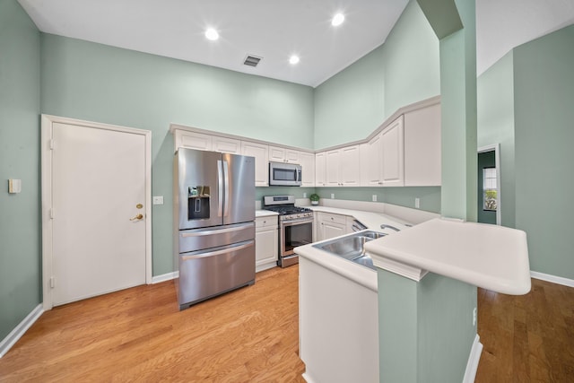 415 NW Granville St, Port Saint Lucie, FL 34986 - kitchen featuring appliances with stainless steel finishes, a towering ceiling, light wood-type flooring, light countertops, and a peninsula