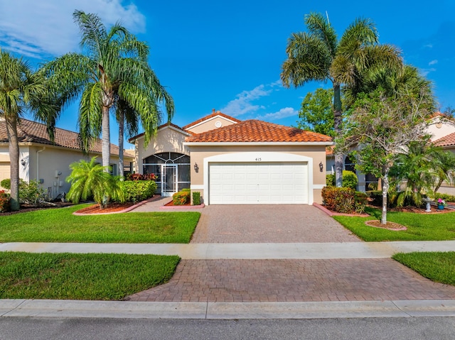 415 NW Granville St, Port Saint Lucie, FL 34986 - mediterranean / spanish-style home with a garage, decorative driveway, a front yard, stucco siding, and a tiled roof