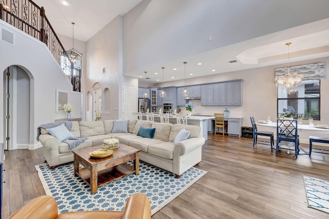 8271 Canopy Ter, Parkland, FL 33076 - living area featuring a chandelier, arched walkways, wood finished floors, a towering ceiling, and baseboards