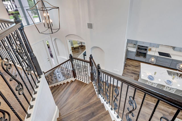 8271 Canopy Ter, Parkland, FL 33076 - staircase with a high ceiling, wood finished floors, a chandelier, and arched walkways