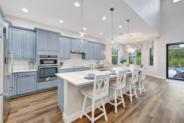 8271 Canopy Ter, Parkland, FL 33076 - kitchen featuring appliances with stainless steel finishes, light wood-type flooring, backsplash, a kitchen island with sink, and recessed lighting