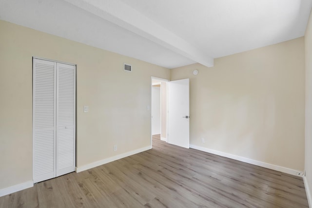 1325 S Flagler Ave Unit 104, Pompano Beach, FL 33060 - unfurnished bedroom with wood finished floors, baseboards, beamed ceiling, and a closet