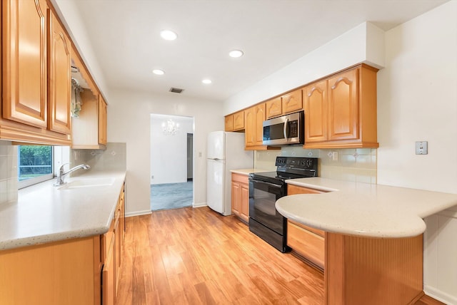 1937 Park Pl, Boca Raton, FL 33486 - kitchen with black range with electric cooktop, stainless steel microwave, freestanding refrigerator, light wood-style floors, and a sink