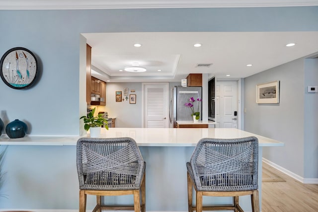 2424 N Federal Hwy Unit 315, Boynton Beach, FL 33435 - kitchen with stainless steel appliances, a peninsula, a breakfast bar area, light countertops, and brown cabinetry