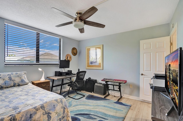 2424 N Federal Hwy Unit 315, Boynton Beach, FL 33435 - bedroom featuring light wood finished floors, a desk, a ceiling fan, baseboards, and a textured ceiling