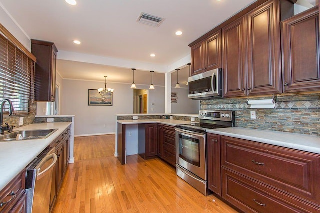 235 30th St, West Palm Beach, FL 33407 - kitchen with stainless steel appliances, a sink, a chandelier, a peninsula, and tasteful backsplash