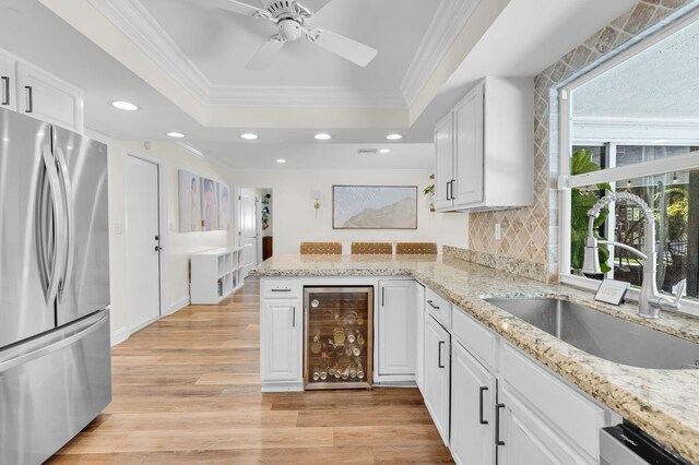 769 Berkeley St, Boca Raton, FL 33487 - kitchen featuring appliances with stainless steel finishes, beverage cooler, a sink, ornamental molding, and a raised ceiling