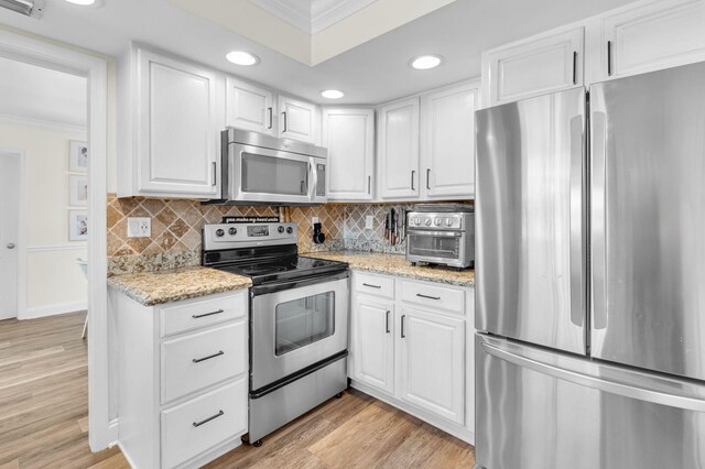 769 Berkeley St, Boca Raton, FL 33487 - kitchen with stainless steel appliances, crown molding, white cabinetry, light wood-type flooring, and tasteful backsplash